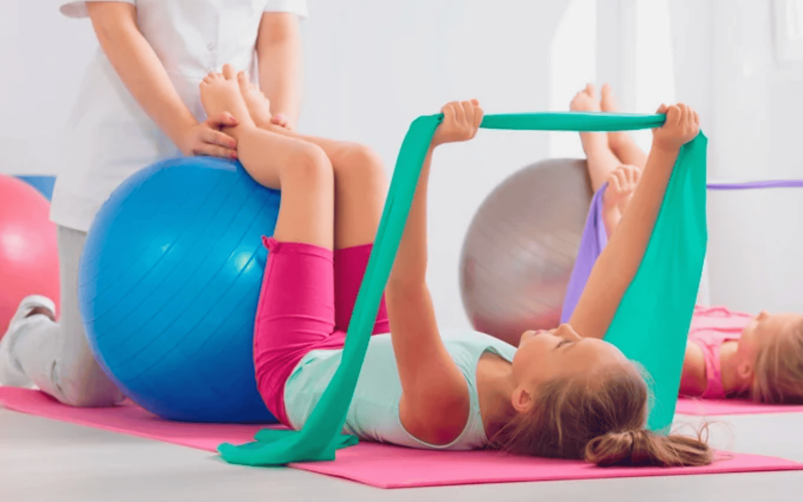 Bambina che fa esercizi con elastico e palla in palestra